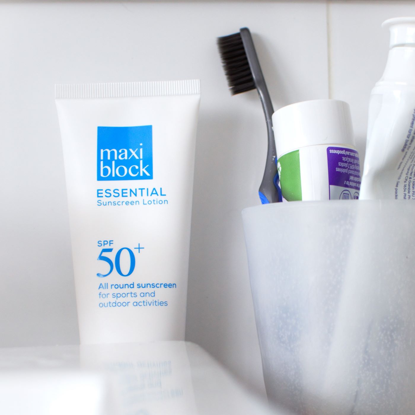 Sunscreen tube on a bathroom shelf next to everyday items like a toothbrush