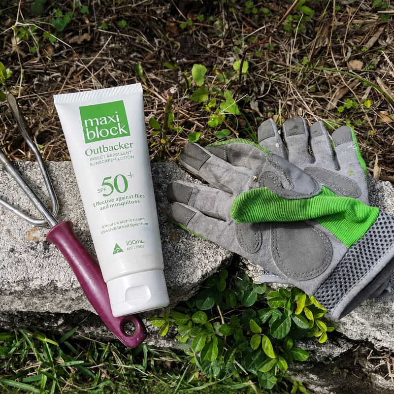 Maxiblock Outbacker 100mL On A Rock Alongside Garden Gloves and Fork