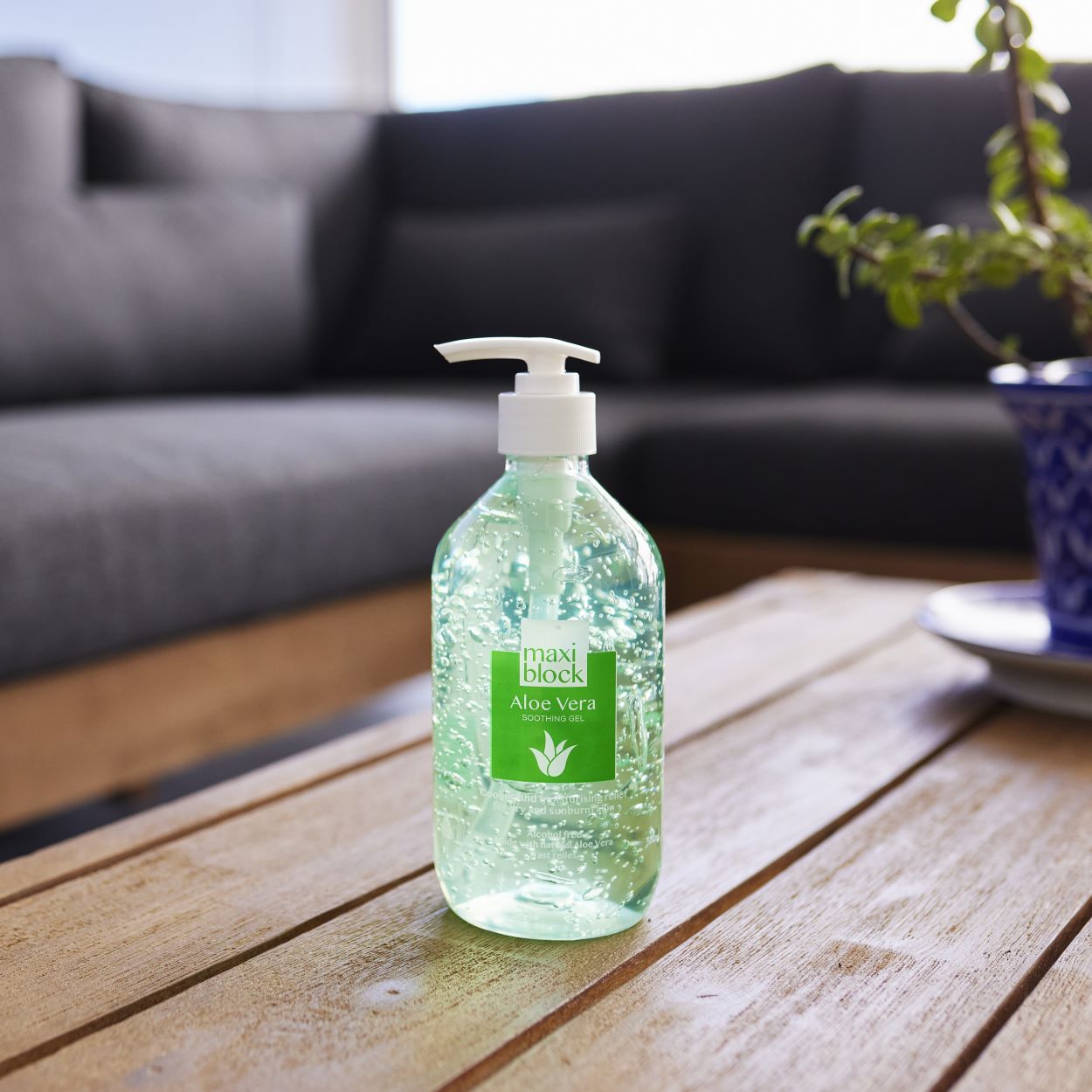 Bottle of Maxiblock Aloe Vera Gel sanitizer on a wooden table with a blurred background