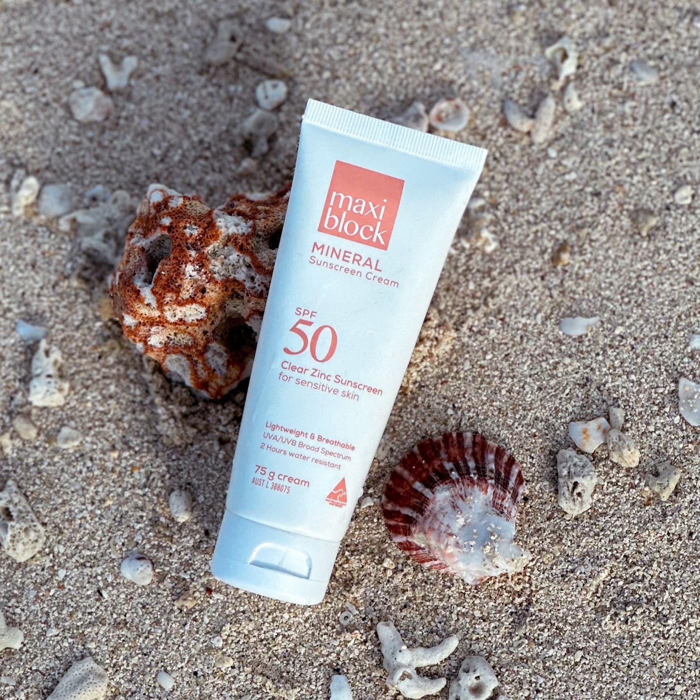 Maxiblock mineral sunscreen tube on sand with shells and coral
