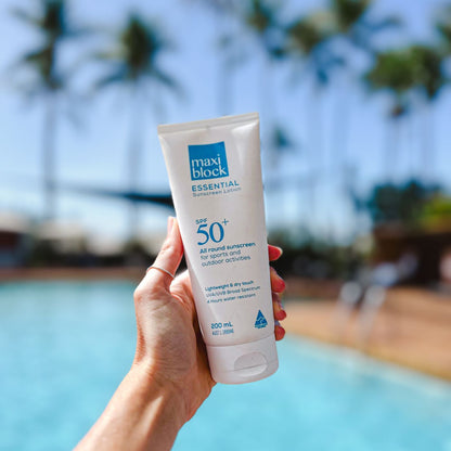 Woman holding sunscreen tube by the pool